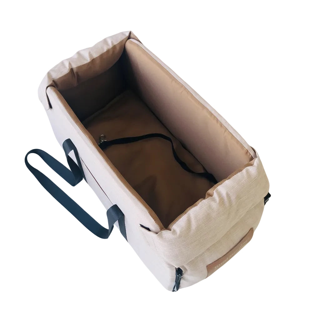 Beige pet carrier with a black strap on a light blue background