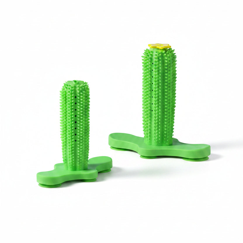Two green textured silicone stand-up grips with flat bases, shown on a pink surface against a light blue background. One has a small yellow accent on top.